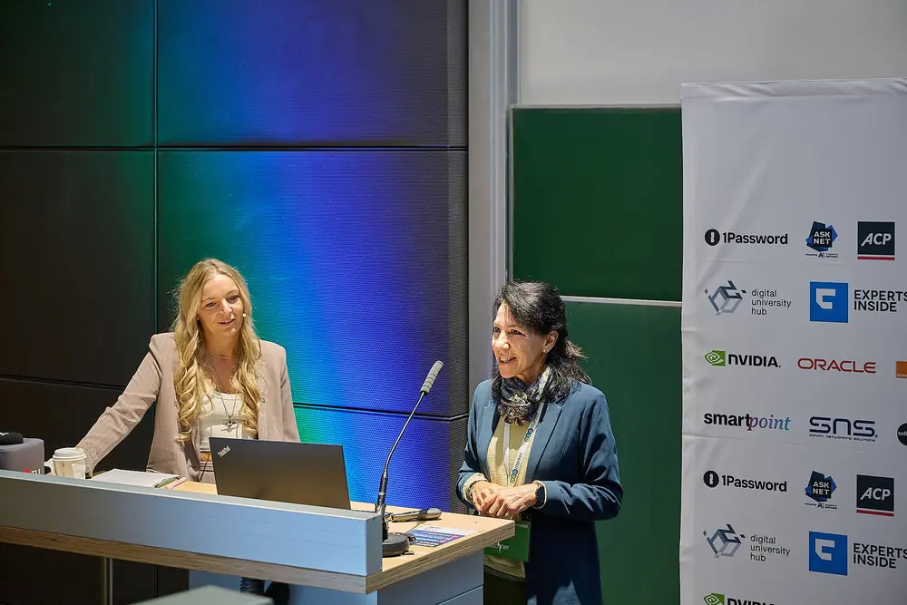 Bettina Lechner auf der Bühne der ACOTEC 2026 an der TU Graz während der Keynote mit dem KI-Avatar